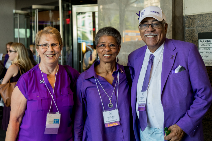 Three long-term survivors and PanCAN volunteers dressed in purple standing united together.