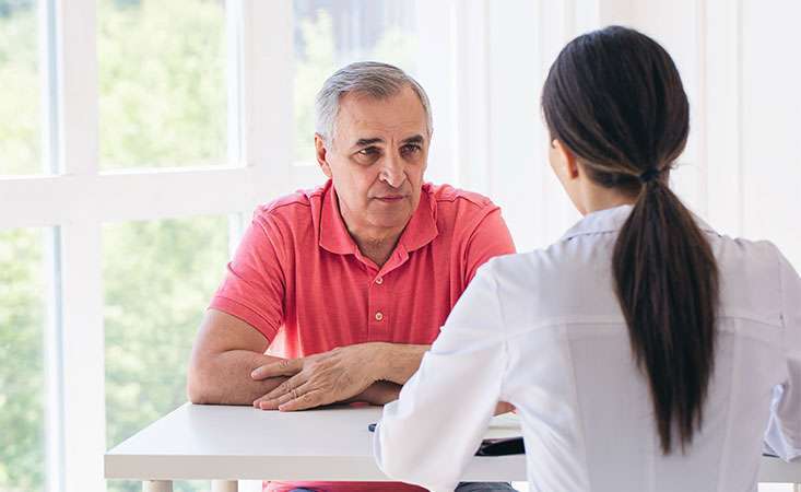 Senior male patient talks to doctor about his pancreatic cancer prognosis 