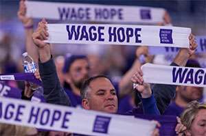 A group of pancreatic cancer supporters stand united holding banners that read “Wage Hope”