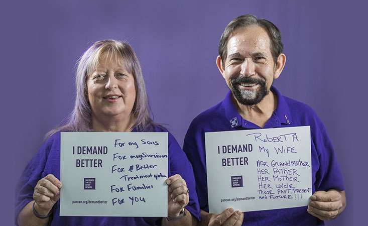 Pancreatic cancer volunteers hold signs saying why they Demand Better