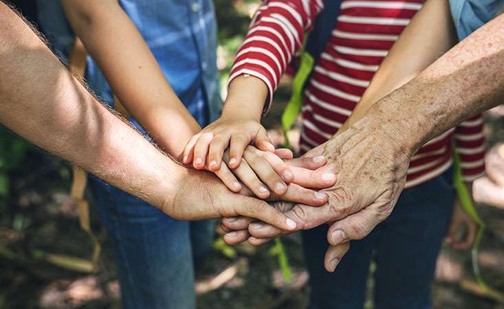 A multigenerational family puts their hands together to support pancreatic cancer awareness