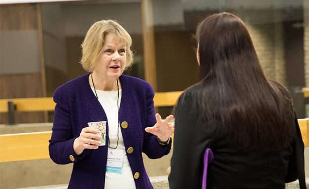 Barbara Kenner, PhD, speaks with a conference attendee about pancreatic cancer research