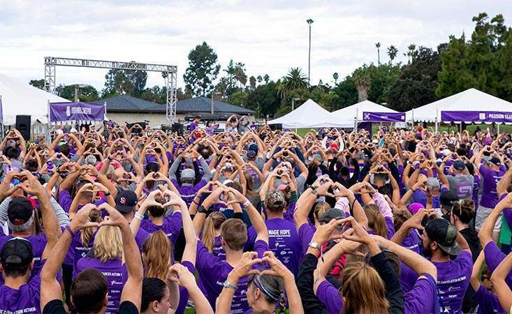 San Diego PurpleStride attendees hold hands up in heart-shaped gesture at pancreatic cancer walk